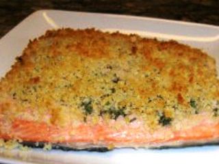 A breaded salmon fillet topped with a crispy, golden breadcrumb crust is perfectly presented on a white square plate. This recipe features a crust seasoned with herbs, offering both texture and flavor while remaining low calorie for guilt-free indulgence.