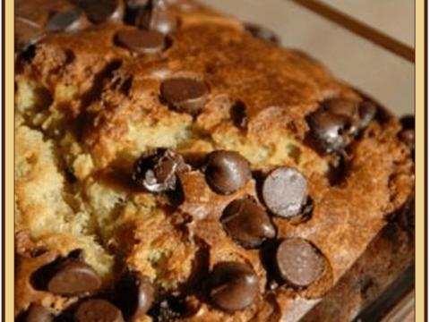 A close-up of a golden-brown loaf of peanut butter chocolate chip banana bread rests on a wooden surface, with deliciously visible chocolate chips. Text at the top offers a tempting peek into this irresistible peanut butter chocolate chip banana bread recipe.