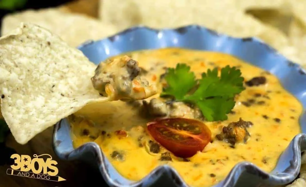 A rotel cheese dip with ground beef with some tortilla chips.