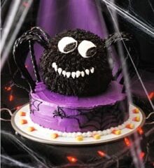 Presenting the Spooky Spider Cake: a Halloween-themed masterpiece with a purple base, intricate spider web designs, and candy corn accents. Crowned by a round black spider-shaped cake with big eyes and a white grin, encircled by black licorice legs. Perfect for any Halloween recipe collection!.