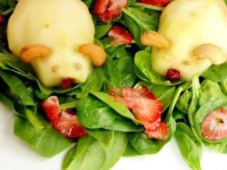 Two pear-shaped mice, crafted from ripe pears with almond ears and raisin eyes, nestle on a spinach salad adorned with sliced strawberries. This whimsical dish adds a touch of charm to any setting, reminiscent of an Easter Bunnys playful feast.