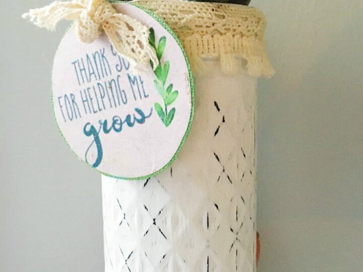 Decorative white mason jar with a lace lid holding a small succulent, featuring a tag that reads “Thank you for helping me grow.”