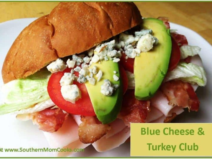 A Club Sandwich with sliced turkey, crispy bacon, lettuce, tomato, avocado, and blue cheese crumbles on a round bun. Text reads Blue Cheese & Turkey Club and includes a website URL at the bottom left.