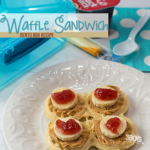 A white plate boasts four mini waffle sandwiches adorned with peanut butter, banana slices, and jelly. In the background sit a blue bento box lid, spoon, napkin, cheese sticks, and a cup of applesauce. Text reads Waffle Sandwich Bento Lunch Recipe.