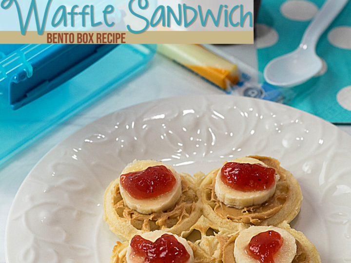 A white plate boasts four mini waffle sandwiches adorned with peanut butter, banana slices, and jelly. In the background sit a blue bento box lid, spoon, napkin, cheese sticks, and a cup of applesauce. Text reads Waffle Sandwich Bento Lunch Recipe.