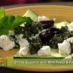Discover the tantalizing Grilled Zucchini with Mint Pesto & Feta recipe, featuring perfectly grilled zucchini crowned with mint pesto, creamy feta cheese, and savory black olives. Fresh mint leaves add a final touch. Text on screen reads Peggy Ks Kitchen Cures.