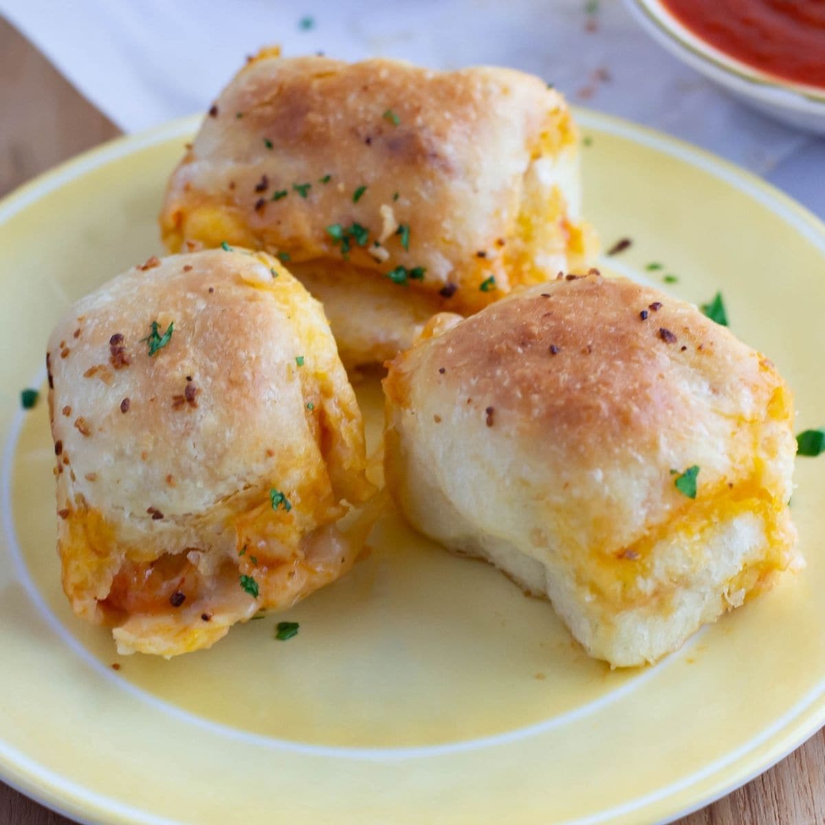 Cheesy pepperoni pizza bombs baked in soft golden dough, served on a plate with melted cheese visible inside.
