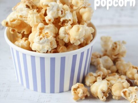 A blue and white striped paper cup brimming with peanut butter popcorn, coated to perfection. Additional fluffy kernels are scattered around, adding to the delicious chaos. In the top right corner, Peanut Butter Popcorn proudly declares its tasty dominance.