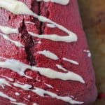 A red velvet biscotti drizzled with white chocolate icing rests on a baking sheet, embodying the rich flavors of a treasured red velvet bread recipe.