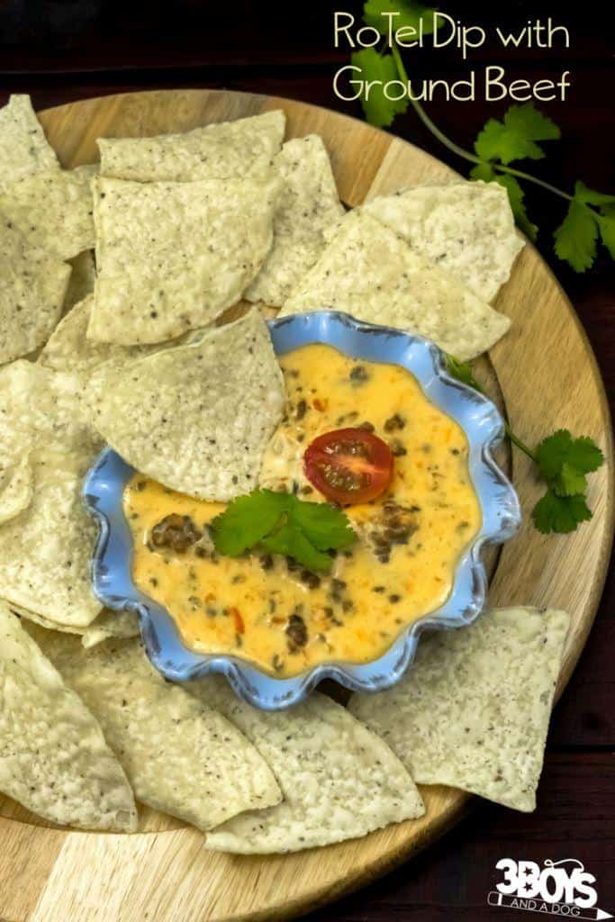 A rotel cheese dip with ground beef with and some tortilla chips.