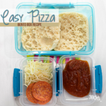 Open bento box with pizza ingredients: two English muffin halves in a larger compartment, shredded cheese and pepperoni slices in one small container, and pizza sauce in another. Text reads Easy Pizza Bento Box Recipe.
