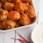 white bowl full of chicken meatballs covered with buffalo sauce