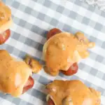 pin image that reads pigs in a blanket easy snack with chili cheese covered pigs in a blanket on a checkered table