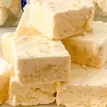 pin image that reads egg nog fudge easy dessert with a stack on fudge on a white plate