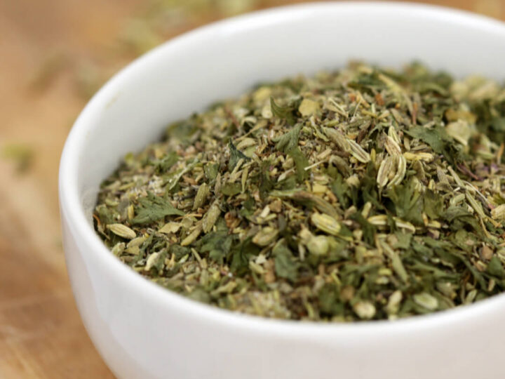 Small white bowl filled with a homemade dried herb seasoning blend on a wooden surface.