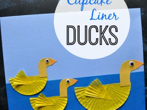 Craft project featuring three yellow ducks made from cupcake liners on a blue background. Text reads Cupcake Liner Ducks at the top, with the website iheartcraftythings.com in the corner. Ducks have googly eyes and paper beaks.