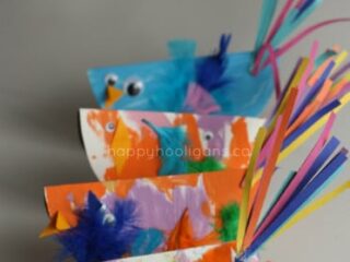 Colorful paper plate birds with googly eyes, feathers, and paper strips for tails are arranged in a row on a neutral background. The text Paper Plate Birds is visible at the top.