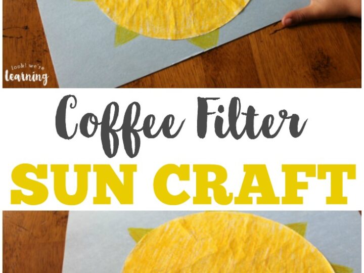 A childs hand touches a sun craft made from a yellow coffee filter on blue paper. The sun has green triangle rays. Text reads, Coffee Filter Sun Craft.