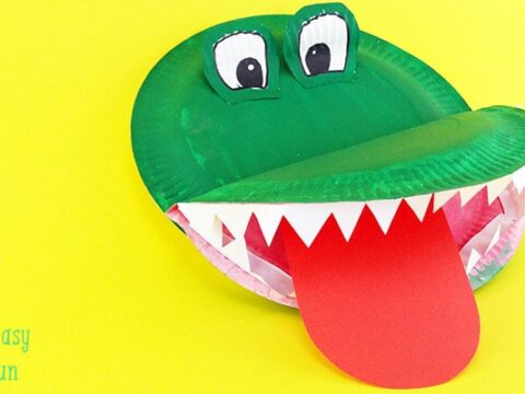 A craft paper crocodile made from a green painted paper plate, featuring big eyes, white triangular teeth, and a red tongue on a yellow background. The text Easy Peasy and Fun is in the bottom left corner.