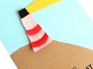 A colorful lighthouse craft made with red and pink striped cupcake liners on a blue and brown paper background, with a yellow light beam. Text at the bottom reads Cupcake Liner Lighthouse Craft.