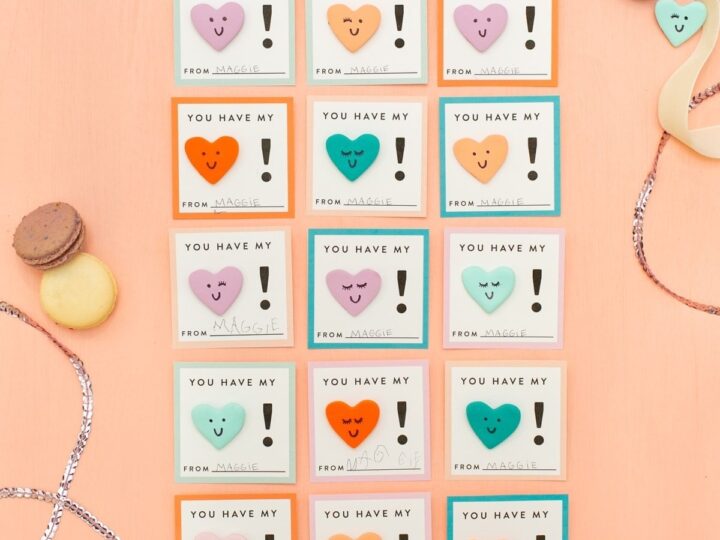 A grid of colorful cards on a peach background, each with a heart and the message You have my heart! Different colors and heart shapes. Surrounded by macarons, small heart trinkets, ribbon, and silver beads.