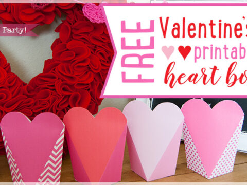 Image of four pink and red heart-shaped boxes in a row. A red heart wreath is in the background. Text reads, Free Valentines Day printable heart boxes in pink and red.