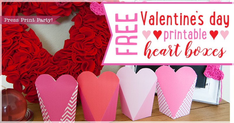Image of four pink and red heart-shaped boxes in a row. A red heart wreath is in the background. Text reads, Free Valentines Day printable heart boxes in pink and red.