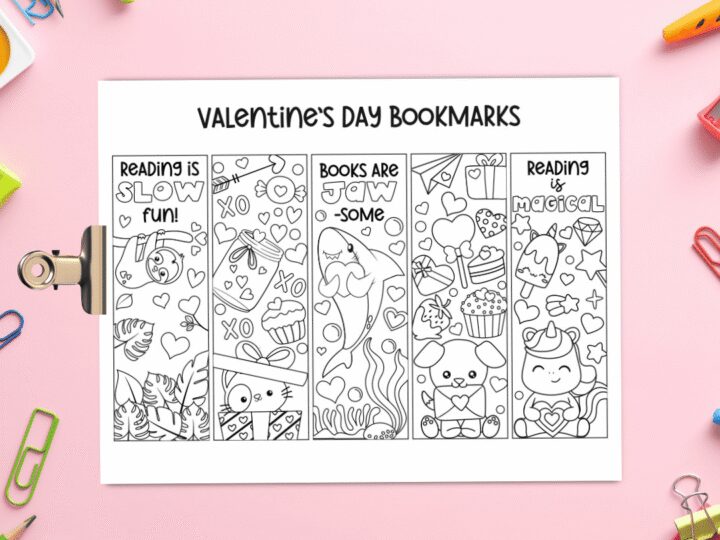 A sheet featuring four Valentines Day bookmarks with cute, themed black and white illustrations. They include animals, hearts, stars, and encouraging phrases. Colorful stationery like paper clips and markers surround the sheet on a pink surface.
