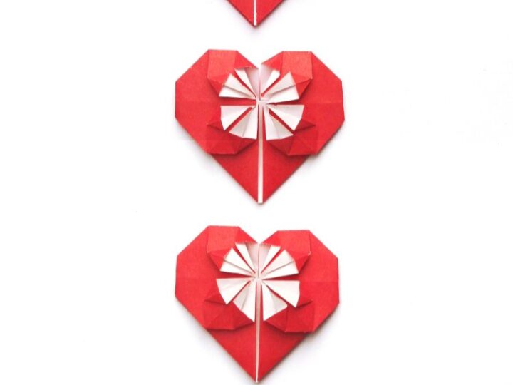 Three red origami hearts are vertically aligned against a white background. Each heart features a white and red decorative pattern. Below them, the text reads, How to Make Origami Hearts.