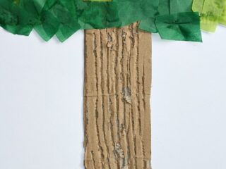 A cardboard tree trunk with vertical grooves, topped with a canopy of layered green tissue paper squares, creating a leafy effect. The background is plain white.