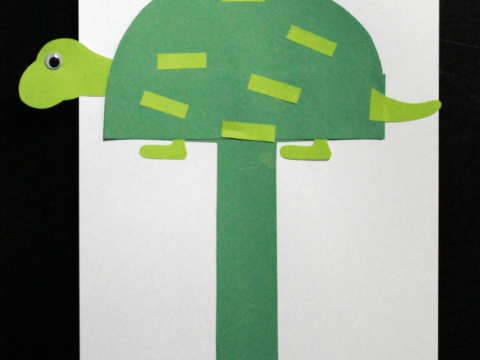 Craft project featuring a green paper turtle on a white background, with a large green letter T underneath. The turtle is decorated with lighter green rectangles. Text reads, Uppercase Letter T and preschool ALPHABET BOOK.