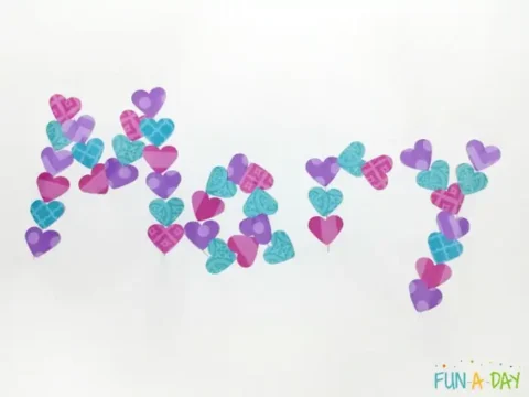 The image showcases the word Mom elegantly crafted from small paper hearts in purple, pink, and blue, capturing the spirit of Valentine’s Day with a charming paper crafts touch.