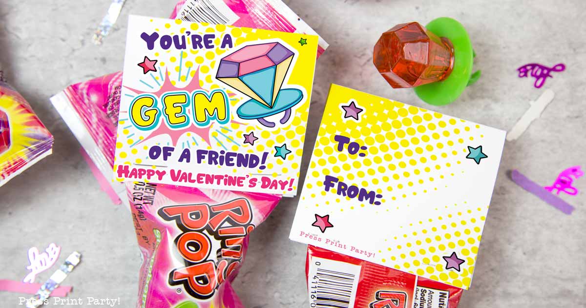 The image features a Ring Pop candy with a colorful Valentines card that says Youre a gem of a friend! Happy Valentines Day! The card has spaces labeled To: and From: surrounded by star and heart graphics. A toy ring is nearby.