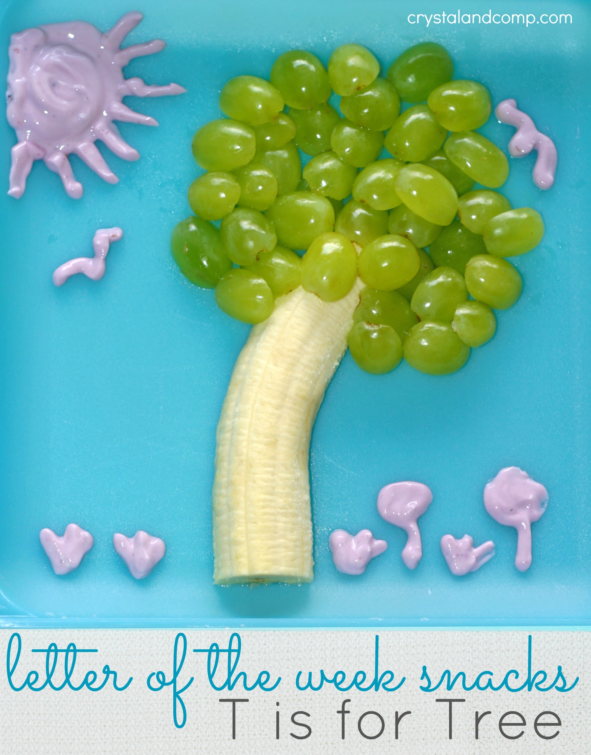 A creative snack on a blue plate resembling a tree: a banana as the trunk and green grapes as the foliage. Pink yogurt forms a sun, birds, and flowers. Text overlay reads, letter of the week snacks: T is for Tree.