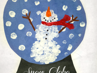 A snow globe craft featuring a snowman created with white fingerprints against a blue background. The snowman has a carrot nose, stick arms, and a red scarf. White dots represent snowflakes. Text below reads Snow Globe Fingerprint Craft.