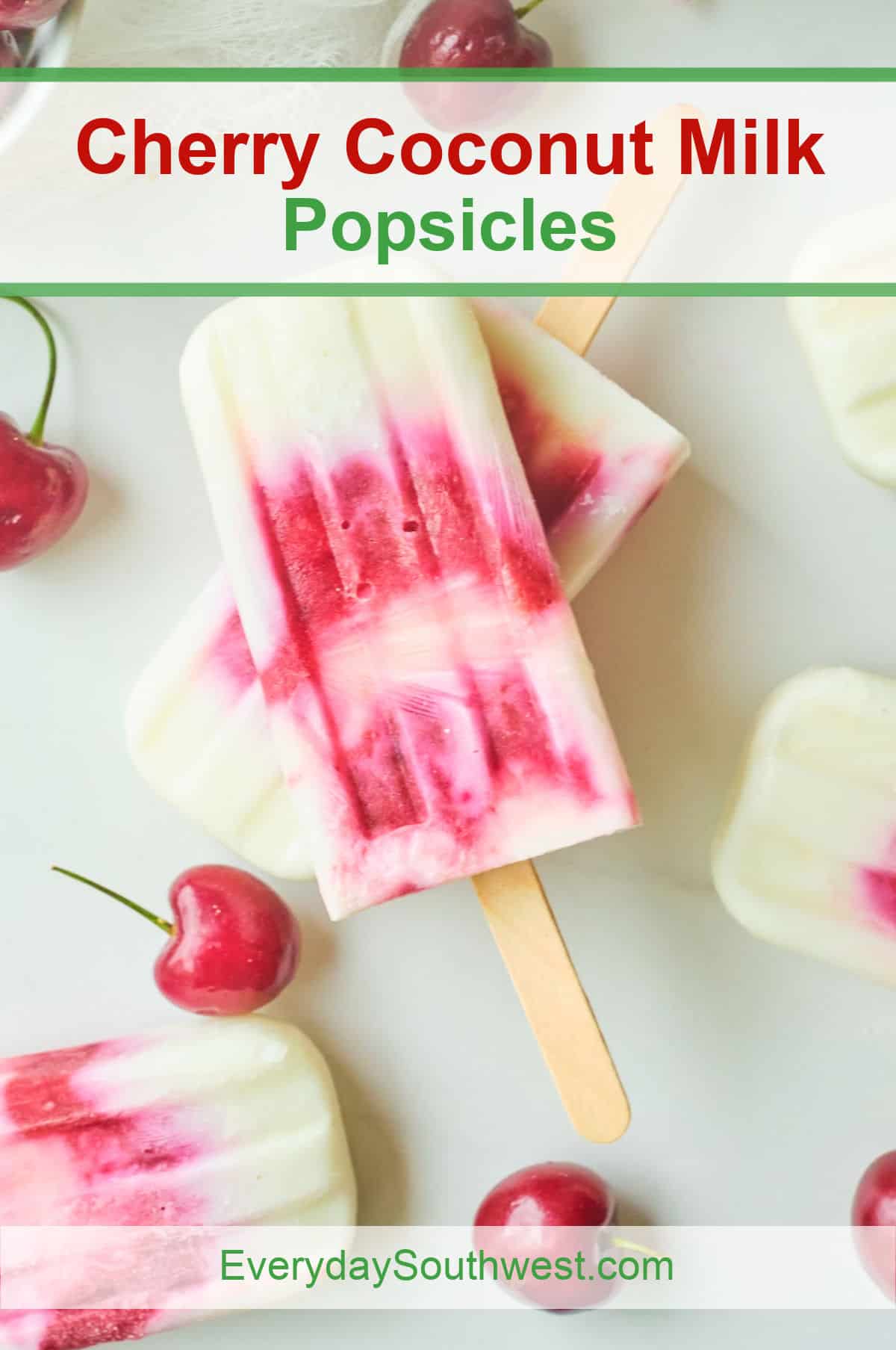 Three cherry coconut milk popsicles on a white surface, surrounded by fresh cherries. The popsicles have a swirled pink and white appearance. Text at the top reads Cherry Coconut Milk Popsicles and EverydaySouthwest.com at the bottom.