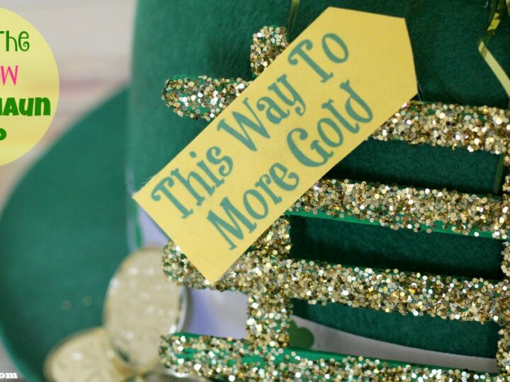 A green hat decorated with a sign that says This Way To More Gold, adorned with glittery gold accents and faux gold coins. The text Under The Rainbow Leprechaun Trap is visible in colorful letters on the left.