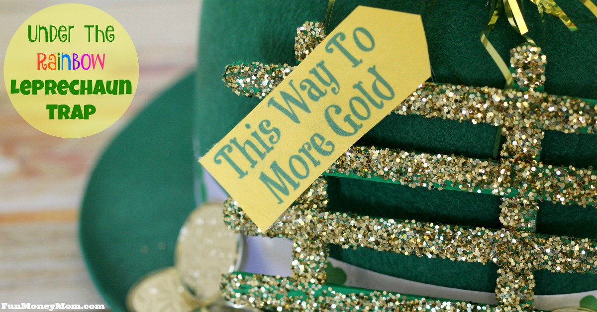 A green hat decorated with a sign that says This Way To More Gold, adorned with glittery gold accents and faux gold coins. The text Under The Rainbow Leprechaun Trap is visible in colorful letters on the left.