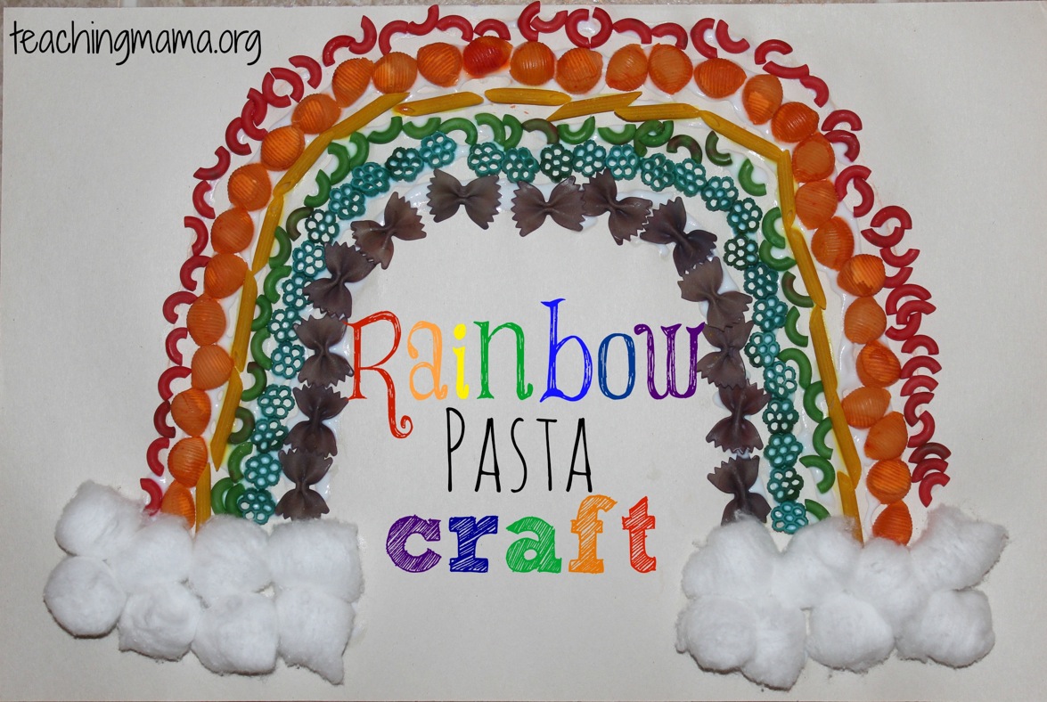 A craft project featuring a rainbow made from colored pasta shapes, including shells, spirals, and bow ties, arranged on paper. Rainbow Pasta Craft is written in colorful letters beneath it. Fluffy cotton balls form clouds at the ends.