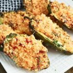 A white square plate holds crispy breadcrumb-coated jalapeño poppers, perfectly arranged and filled to the brim. Ideal for an air fryer recipe, these spicy delights rest on a black and white checkered cloth peeking from the background.