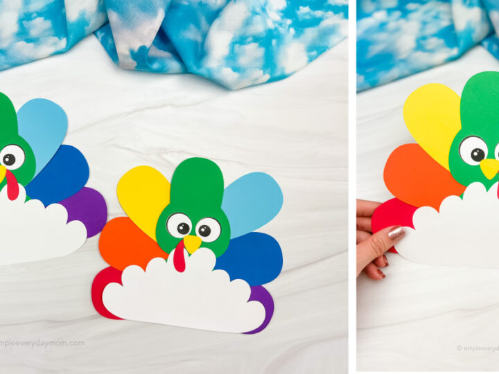 Two colorful turkey crafts made of paper with rainbow tail feathers. Each turkey has a green head, googly eyes, and an orange beak, set against a marbled white surface. A hand holds one turkey on the right. Blue and white fabric in the background.