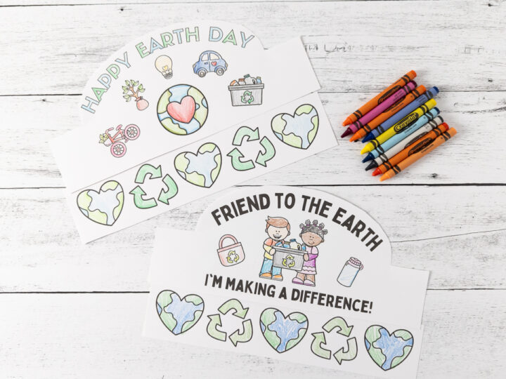 Two Earth Day-themed coloring sheets with drawings of hearts, recycling symbols, and Earths. The top sheet says Happy Earth Day, and the bottom says Friend to the Earth Im Making a Difference! Crayons are beside the sheets on a wooden surface.