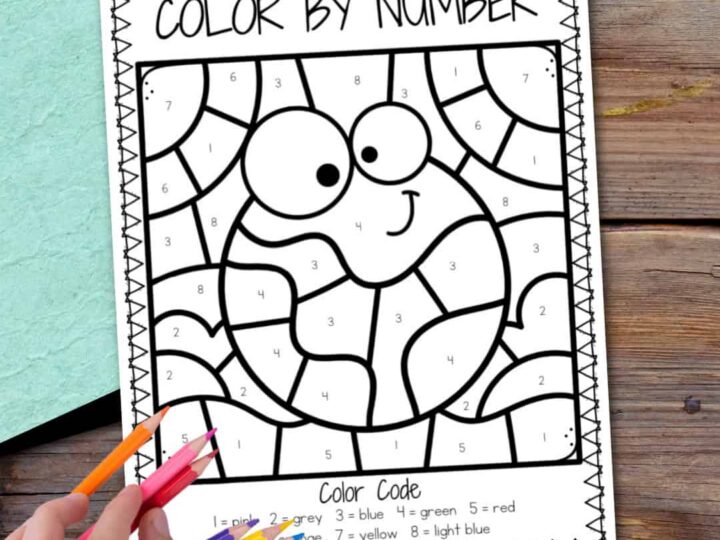 A Color by Number coloring page featuring a cartoon turtle with large eyes, outlined in segments numbered 1 to 8. A hand holds colored pencils over a wooden surface. A color code assigns different colors to each number.