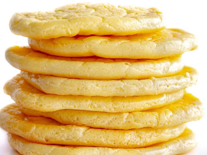 A stack of six fluffy, golden-brown cloud bread slices piled on top of each other against a white background. The bread appears light and airy with a slightly textured surface. Wholesome Yum is written in the bottom right corner.