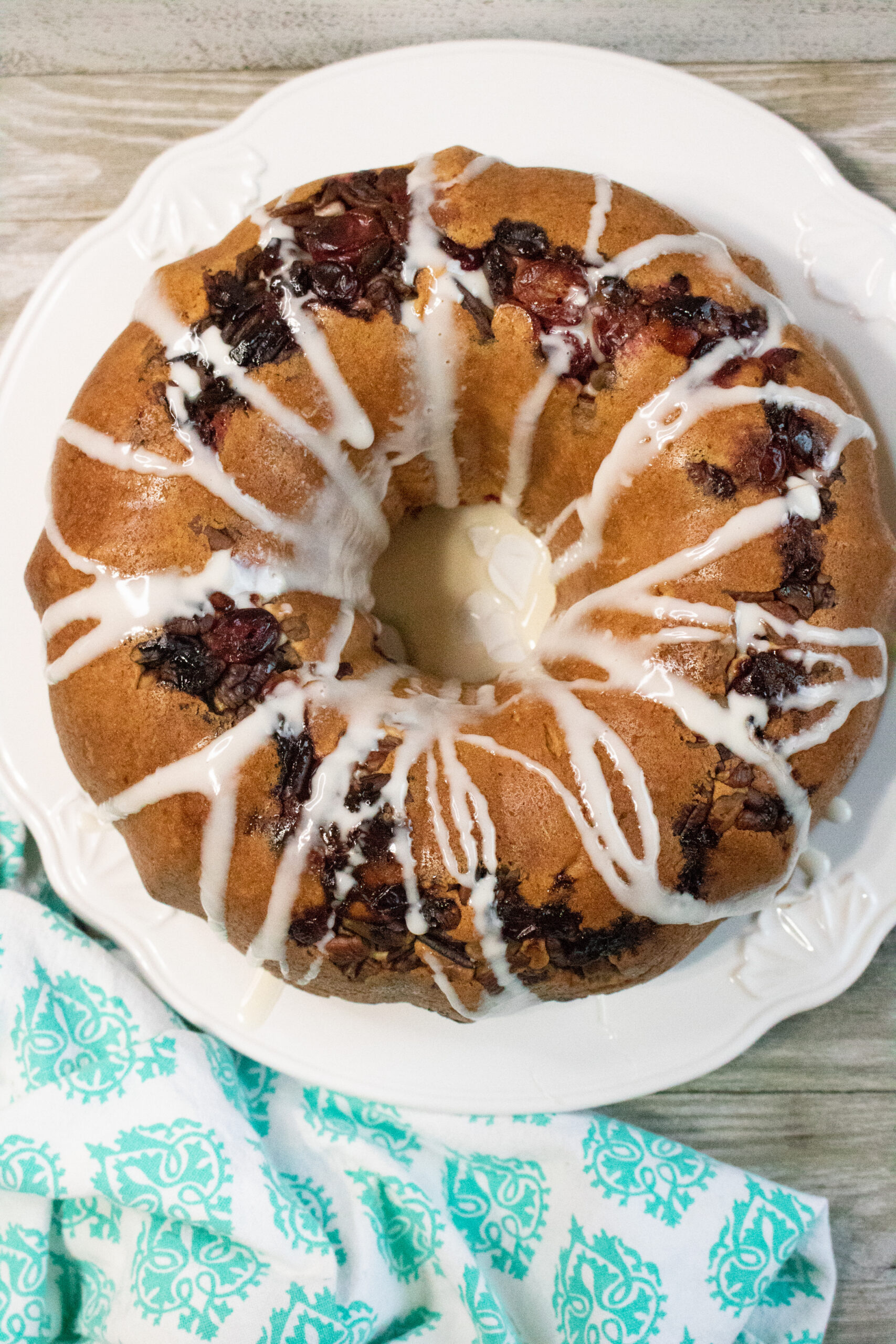 Overhead view of a glazed cranberry pecan bundt coffee cake topped with fresh cranberries and chopped pecans