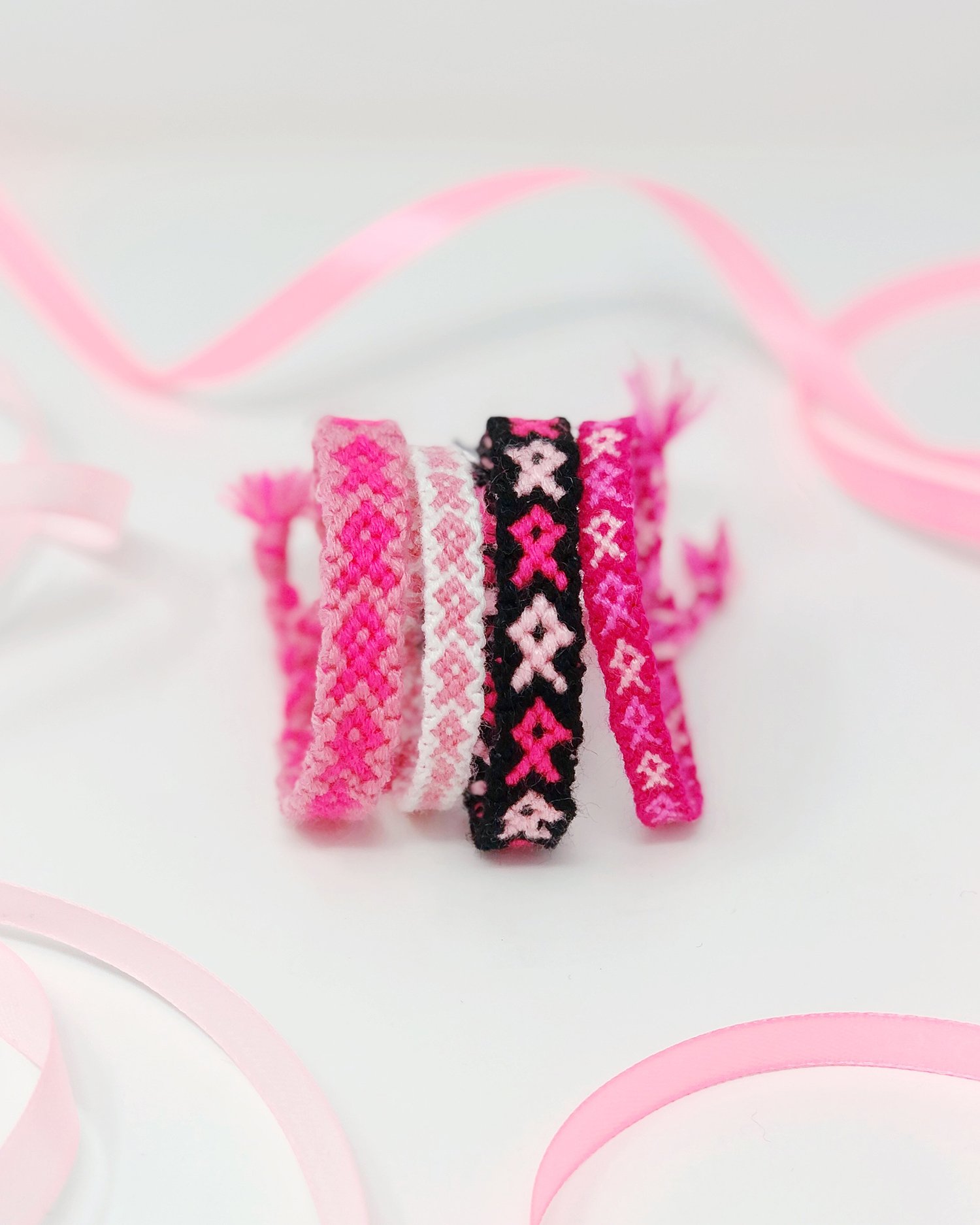 Handmade friendship bracelets with a pink ribbon pattern woven in