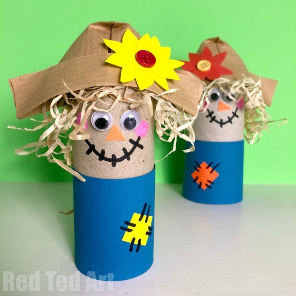 Toilet paper roll scarecrow with an origami paper hat and straw hair