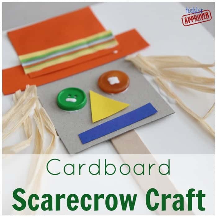 Cardboard scarecrow craft on a popsicle stick stake with button eyes and raffia hair