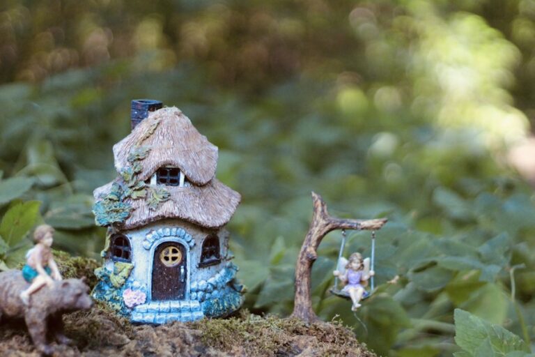 Miniature fairy house with tiny fairy figures in a woodland garden