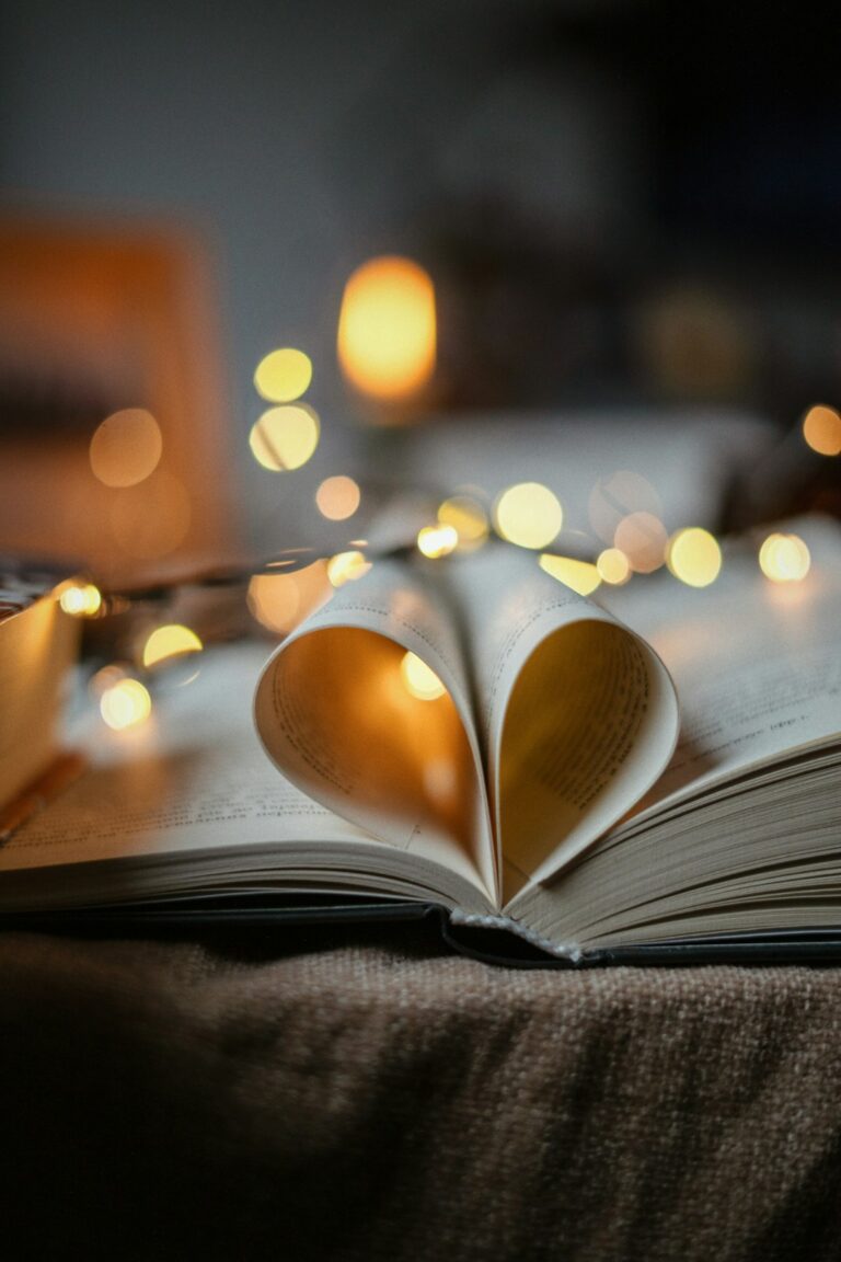 Open book with pages folded into a heart, surrounded by glowing fairy lights